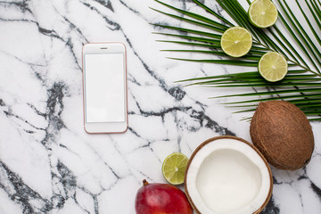 Mobile phone and tropical fruits on marble background