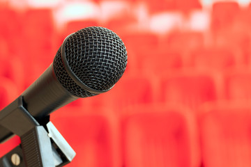 microphone on the stand in an empty assembly hall with red chairs. concept of trainings, business...