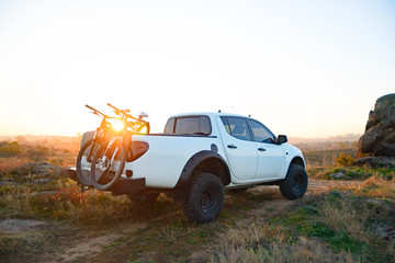 Pickup Offroad Truck with Bikes in the Body in the Mountains at Sunset. Adventure and Car Travel Concept. - obrazy, fototapety, plakaty
