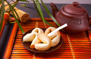 Cup of tea with fortune cookies, teapot in oriental style on a wooden tray