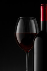 Red wine bottle and glass on the black background