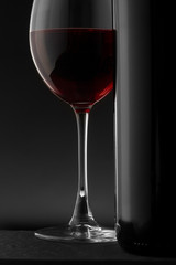 Red wine bottle and glass on the black background