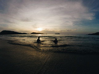 Two people watching peaceful sunset in the ocean