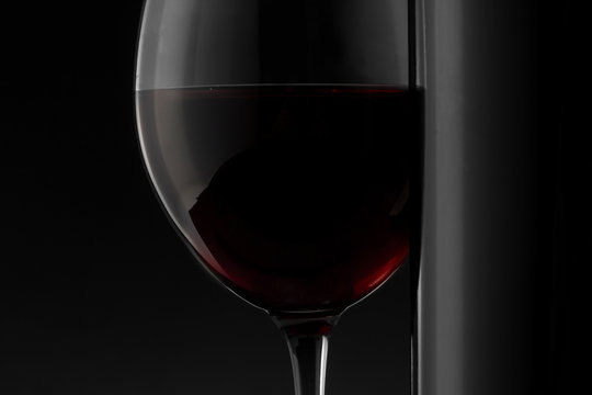 Red wine bottle and glass on the black background