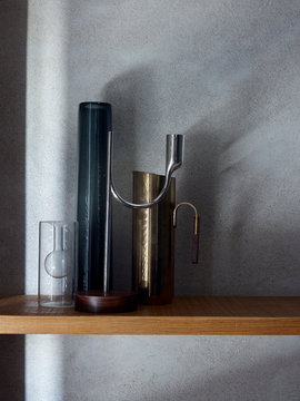Silber Kerzen Leuchter und zwei Glas Vasen und Messing Vase auf Holzregal mit Schattenspiel 
