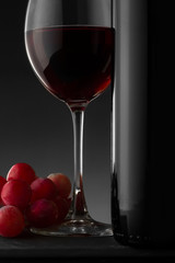 Red wine bottle and glass on the black background