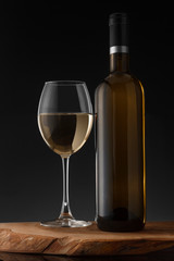 White wine bottle and glass on the black background