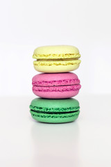 Yellow, pink and green french macarons on the white table. Close-up, front view, copy space