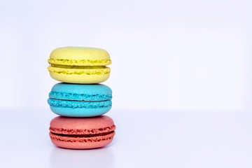 Yellow, blue and brown french macarons on the white table. Close-up, front view, copy space