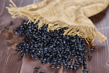 Lot of whole raw black turtle beans spilled on brown wood