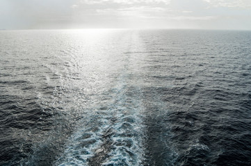 Traces of waves and foam on the surface of the blue sea with a copy of the space at sunset