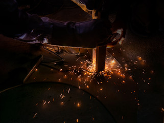 Man welding steel with sparks in the dark.