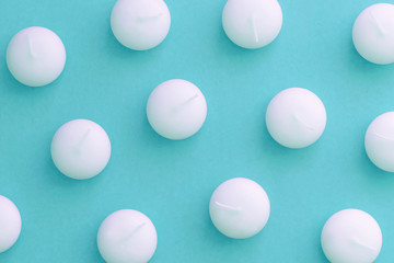 White round candles pattern on the light blue background, toned. Top view, copy space, flat lay, close-up