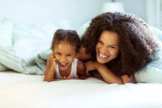 Portrait of happy mother with daughter in bed