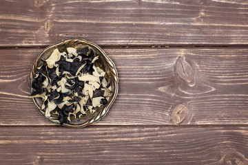 Lot of slices of dry black mushroom jew ear variety in old iron bowl flatlay on brown wood