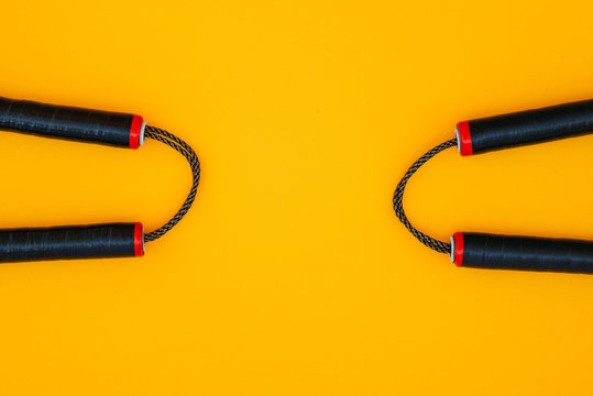 Two nunchats on a yellow background, flat lay. Nunchaku for training