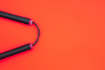 Nunchaku for training on a red background. Copyspace