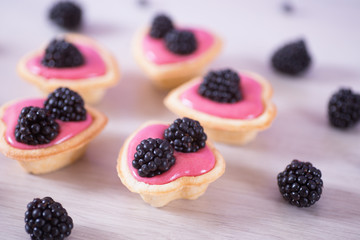 Closeup pink berry yogurt decorated with blackberries in five heart-shaped tartlets.