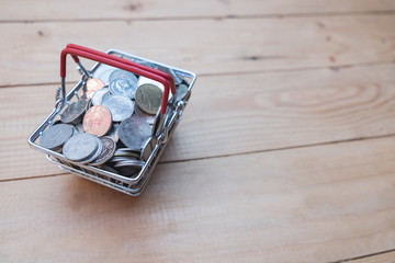 Close up coin in basket on wooden table of brown, saving money concept
