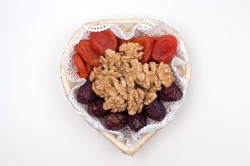 Dates, dried apricots and walnuts in a wicker plate on the white background. Top view, copy space