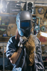 woman with welding mask in workshop - obrazy, fototapety, plakaty