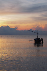 Fototapeta na wymiar Sunrise, the colors of the morning sky, with the fishermen preparing the boat to go out to fish.