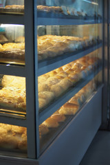 Many kinds of breads are arranged for sale in glass cabinets.