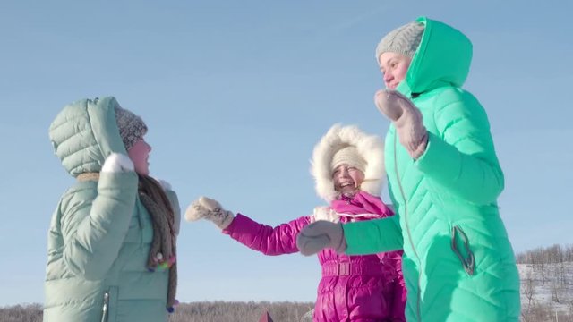 Three children in winter clothes have fun jumping on a frosty afternoon on a walk. Outdoor games in winter