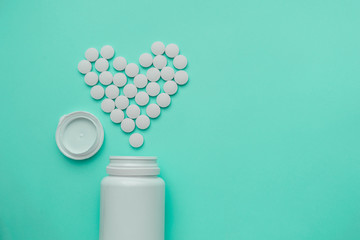 Medicines white, round heart shaped pills isolated on turquoise background.