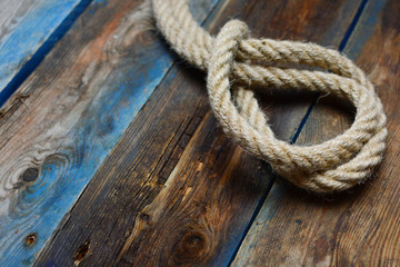 Fototapeta na wymiar Rope loop. Noose closeup. Nautical rope knot on a weathered wooden desk