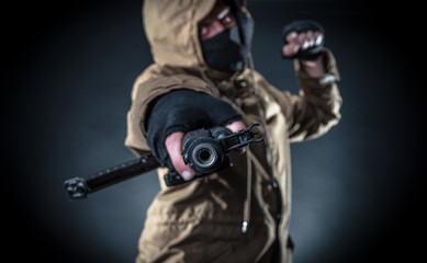 Dangerous armed terrorist with mask and machine gun on dark background. Concept of terrorism and...