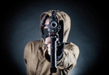 Dangerous armed terrorist with mask and machine gun on dark background. Concept of terrorism and violence.