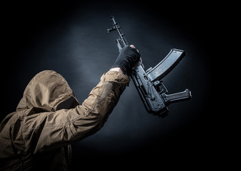 Dangerous armed terrorist with mask and machine gun on dark background. Concept of terrorism and violence.
