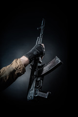 Hand of a dangerous armed terrorist with a machine gun on a dark background.