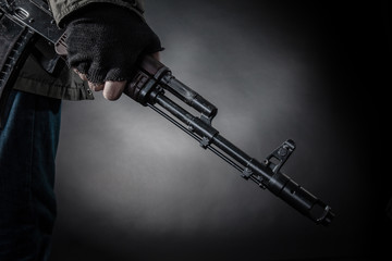 Hand of a dangerous armed terrorist with a machine gun on a dark background.