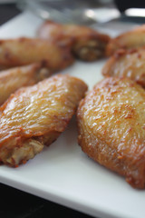 BBQ chicken wings on a white plate served on a black wooden table.