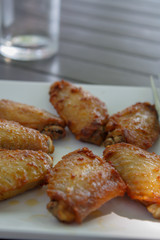 BBQ chicken wings on a white plate served on a black wooden table.