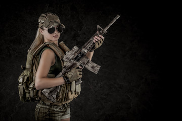 Sexy girl wearing military style posing with guns and sunglases isolated in studio