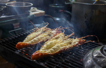 Lobster marinated in a butter and garlic sauce on an open grill at a seafood night market in...