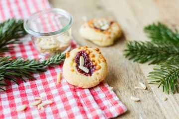 Weihnachten - Kekse mit Marmelade und Mandeln auf Holz und rot karierten Küchentuch