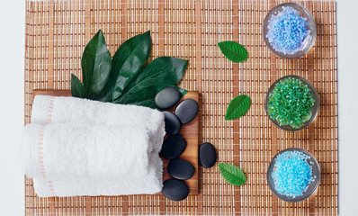 Fototapeta na wymiar Top view of hot stones setting for massage treatment on blackboard with copy space.Towel, Salt, Plumeria Flower, Bowl for spa therapy with Copy space. Beautiful spa composition on massage table