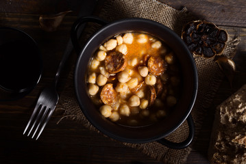 homemade chickpea stew with bread and wine on rustic wooden board illuminated in chiaroscuro