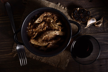 Homemade stew of lamb's liver on rustic wooden board illuminated in chiaroscuro