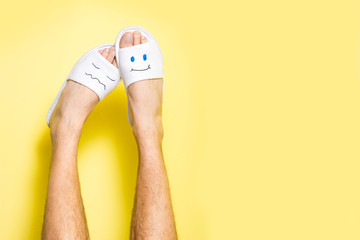 Male legs wearing funny slippers with faces