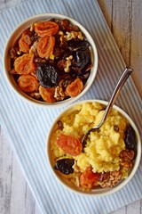 Useful porridge of corn grits and dried fruits on a wooden background.