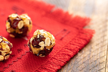 Round energy balls handmade from is lying on red napkin on wooden table.