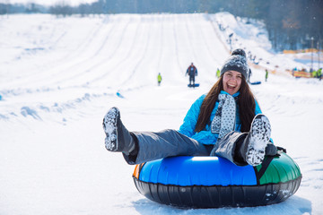 young smiling girl ride sleigh snow tubing hill winter activity