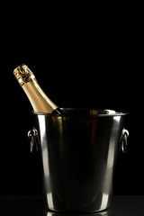 Champagne bottle in bucket on black background