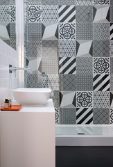 Modern loft bathroom with high ceiling in eaves, walk in shower and monochrome black and white wall tiles.
