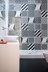Modern loft bathroom with high ceiling in eaves, walk in shower and monochrome black and white wall tiles.